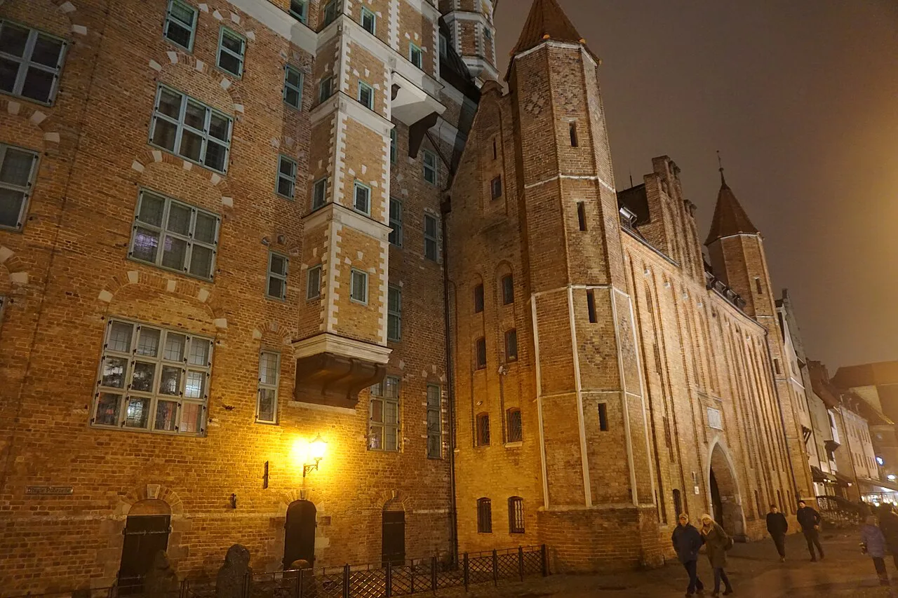 Brick buildings and towers on the Long Embankment (Długie Pobrzeże) in Gdańsk at night.