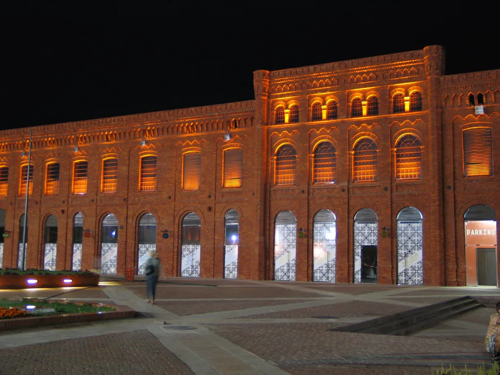 Manufaktura's red-brick factory building lit up at night in Łódź.