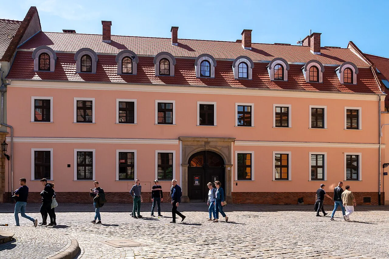 Visitors walking past a building on Ostrów Tumski in Wrocław.