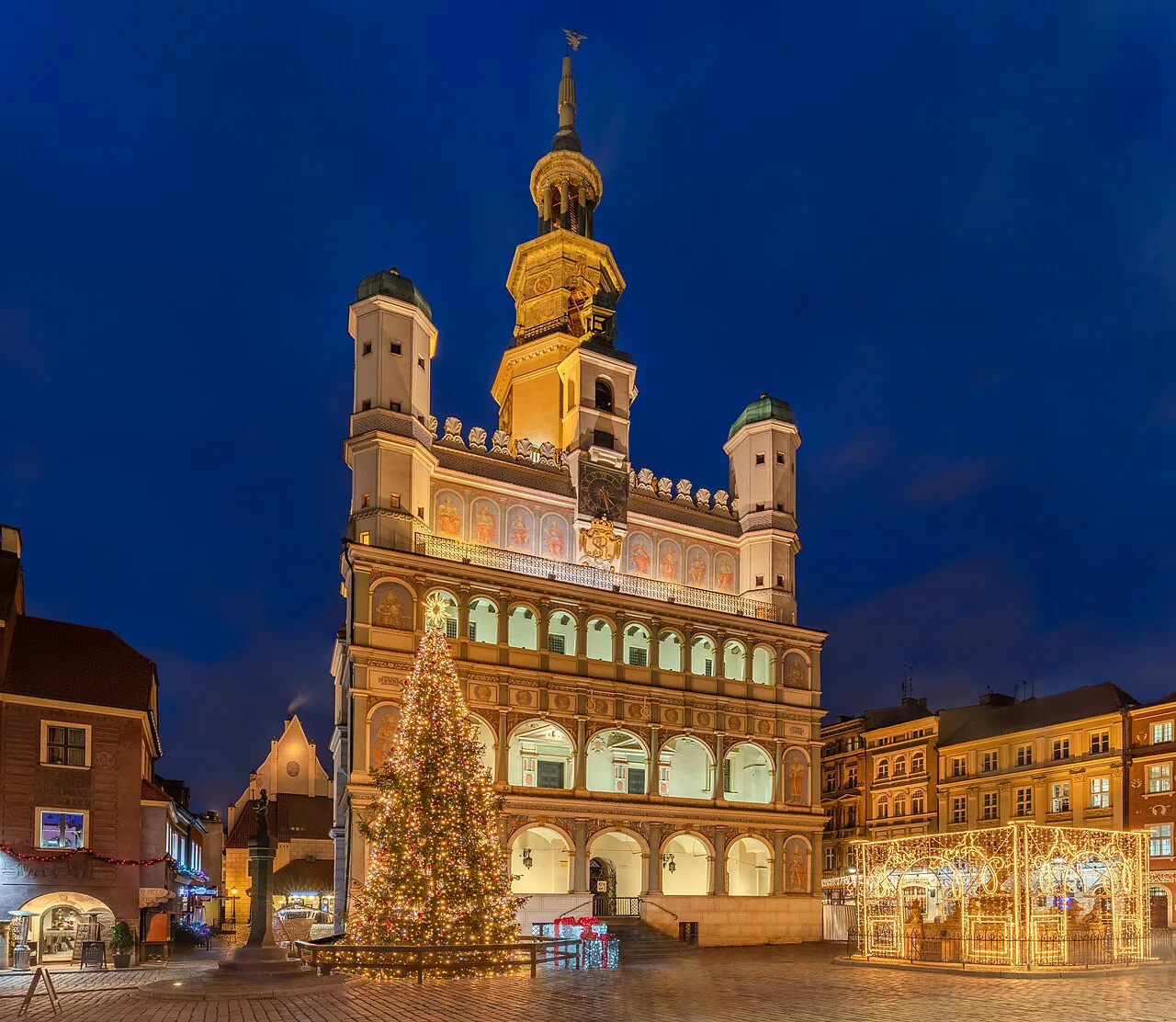 Poznań Town Hall lit up at night, with a Christmas tree.