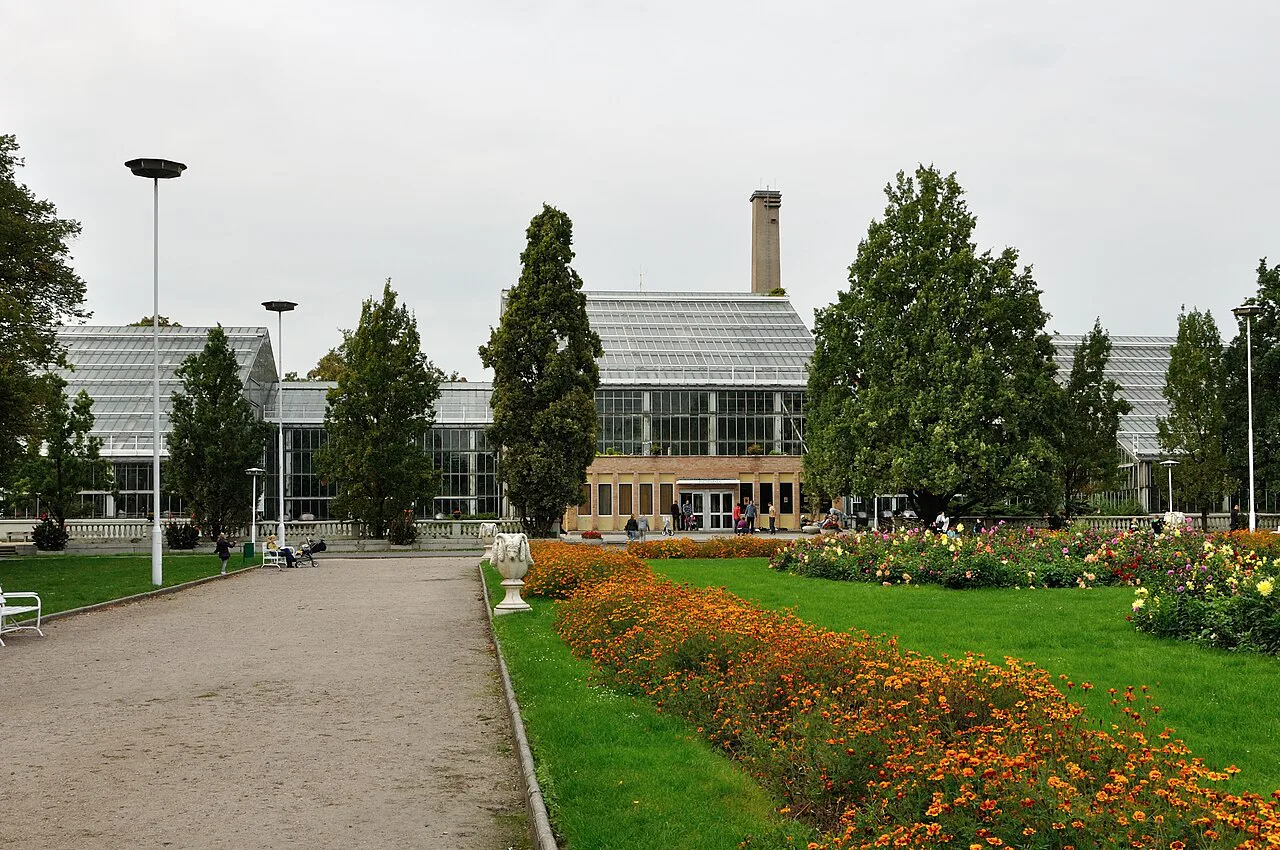 The Palm House in Poznań behind flower beds.