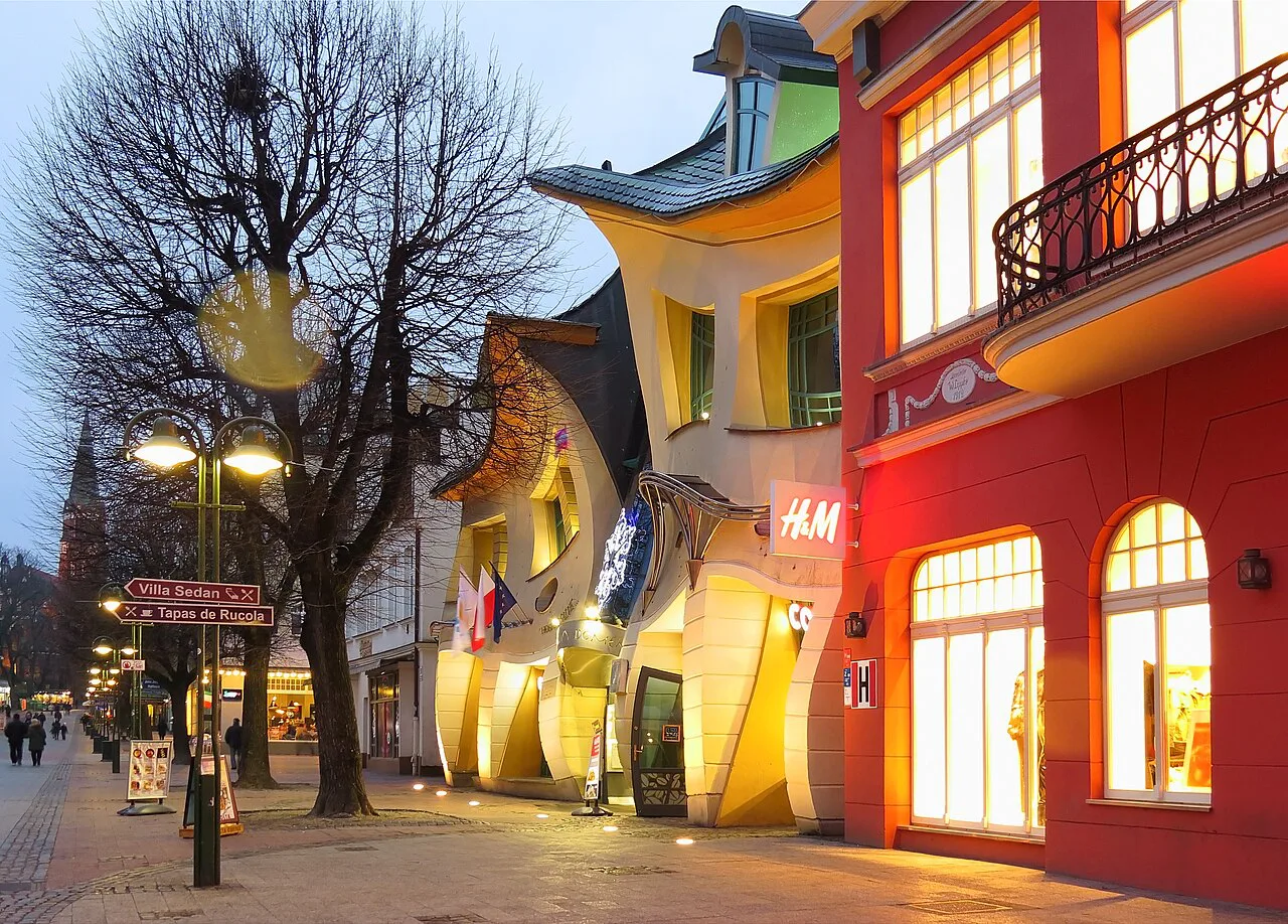 The Crooked House in Sopot lit up at dusk.