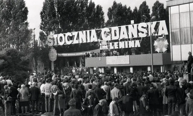 A historic photo of Gdańsk residents gathered at Gate No. 2 of the Lenin Shipyard.