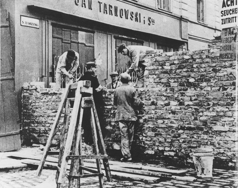 Historic photo of the Warsaw Ghetto wall being built across Świętokrzyska Street.