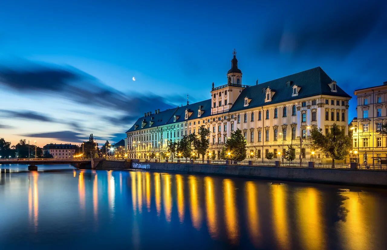 The main building of the University of Wrocław reflected in the Oder at dawn.