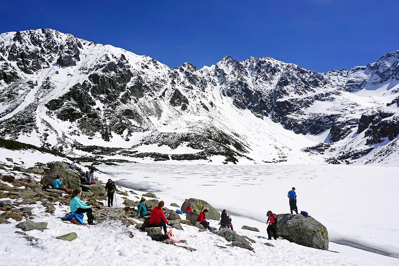 Hikers resting by Czarny Staw Gąsienicowy in the Tatra National Park.