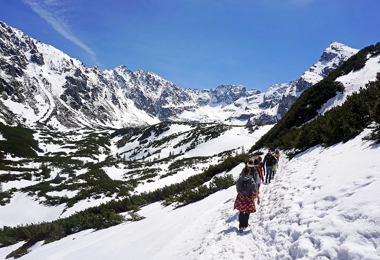 Hikers on the snowy trail towards Czarny Staw Gąsienicowy in the Tatra National Park.